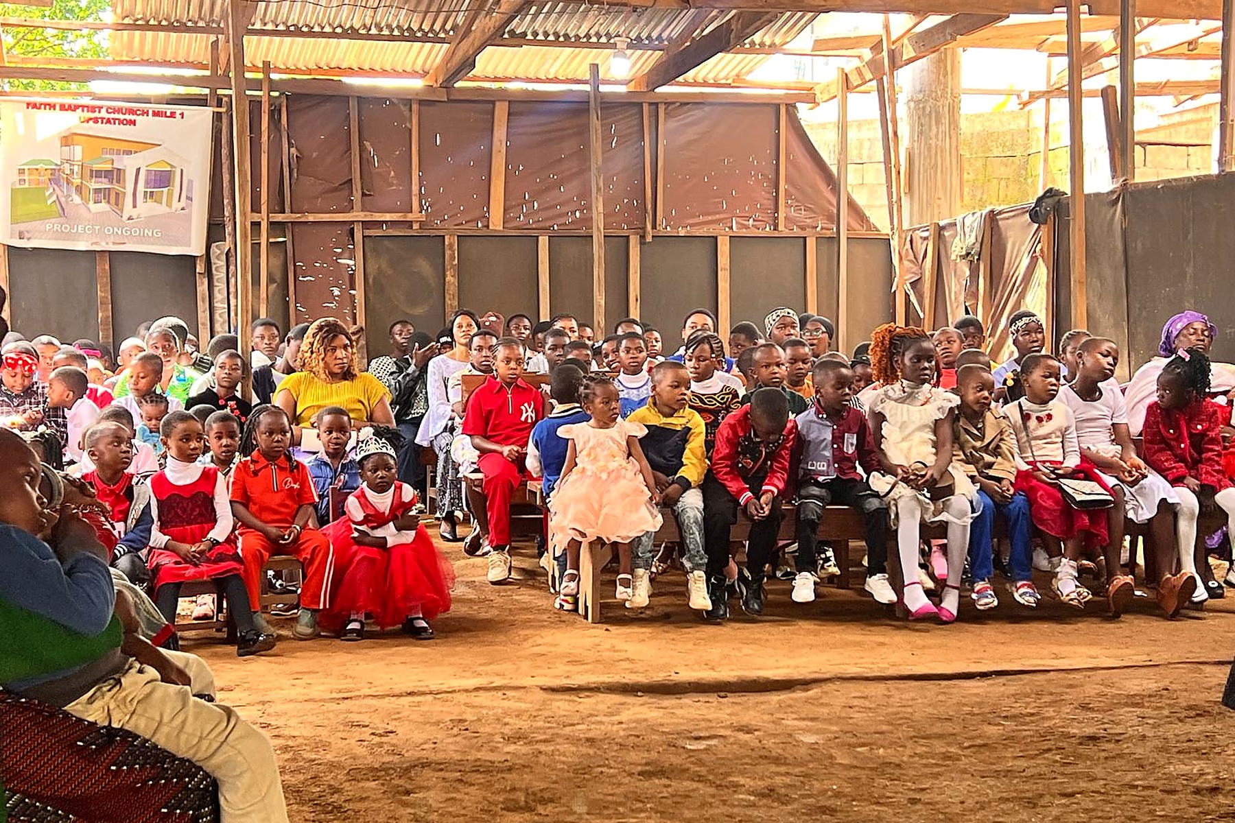 Children and community members gathered at a field programme